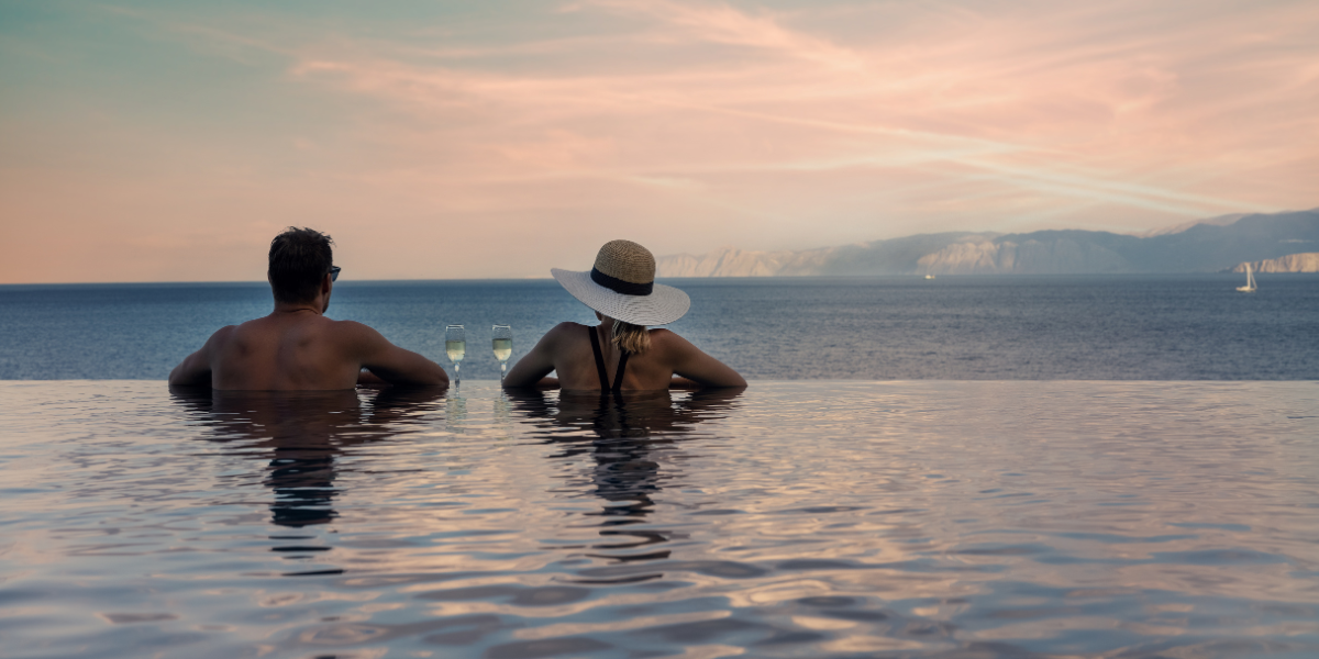 Man and woman on the edge of a pool looking at the view