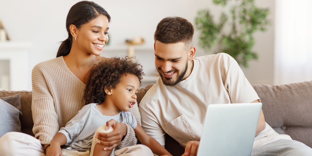 Family of three using a laptop on the sofa