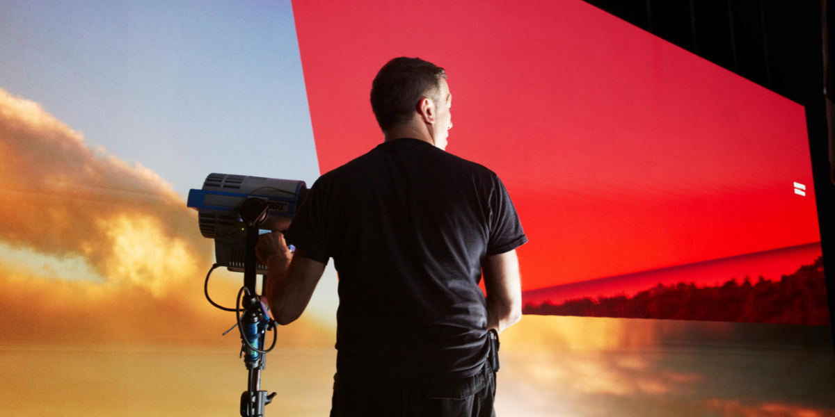 man operating camera infront of screen