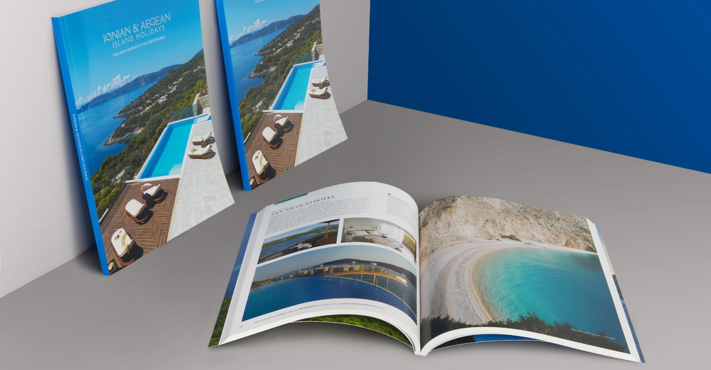 Ionian & Aegean Island Holidays brochures leaning against a white wall and one brochure laying on a grey table