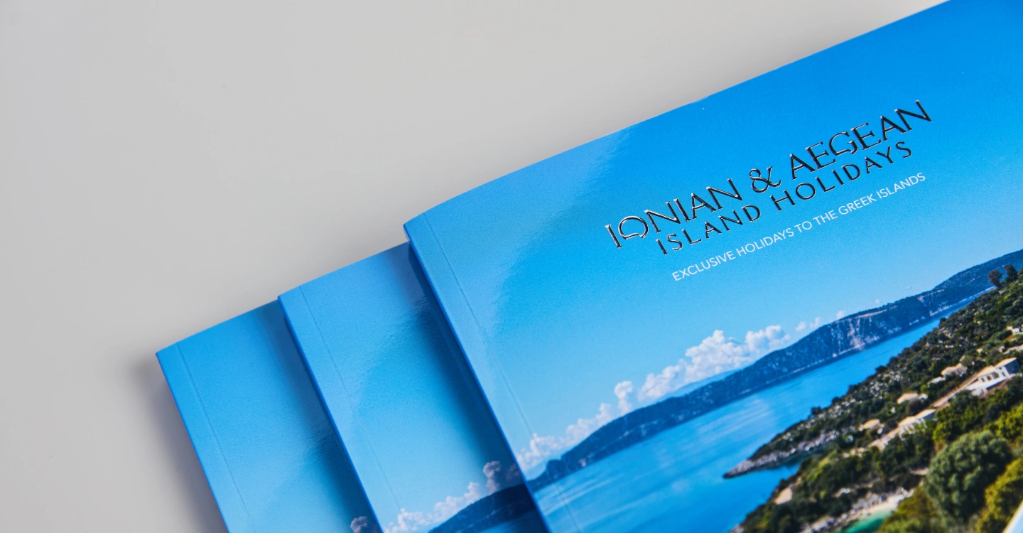 Three Ionian & Aegean Island Holidays brochures laying on a grey table