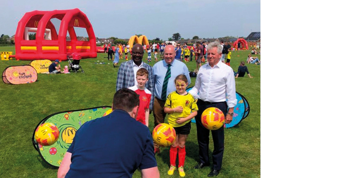 Children and adults posing for camera with footballs
