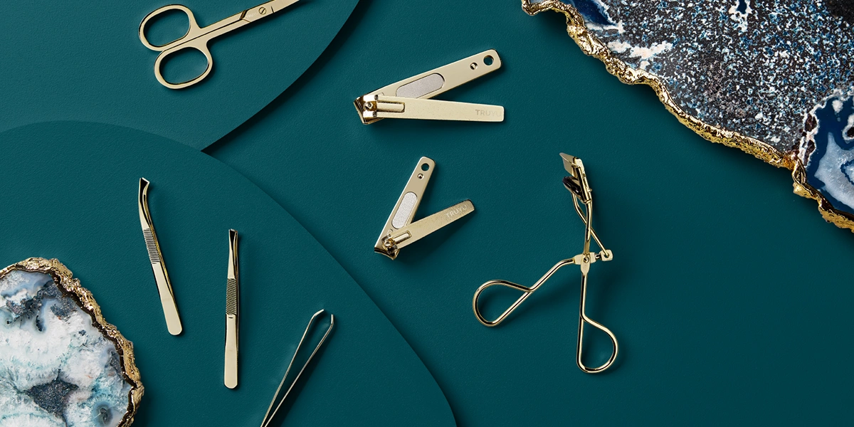 TRUYU gold cosmetic tools laid out on a navy background with gemstones in the background