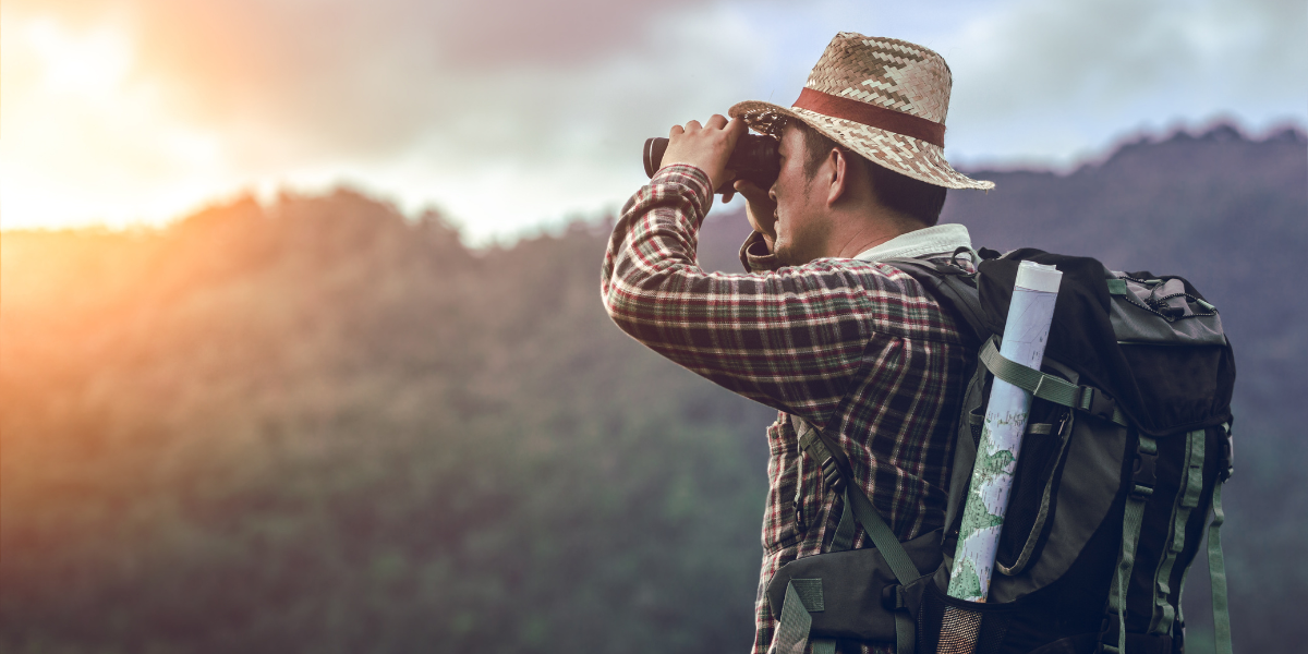 Man with binoculars looking at trees