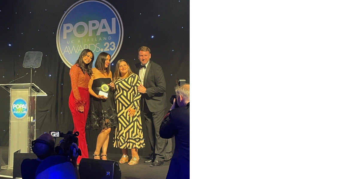 holding an award for a picture at the POPAI awards