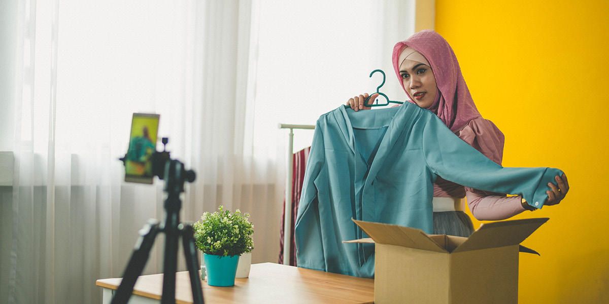 Lady holding shirt talking into a camera