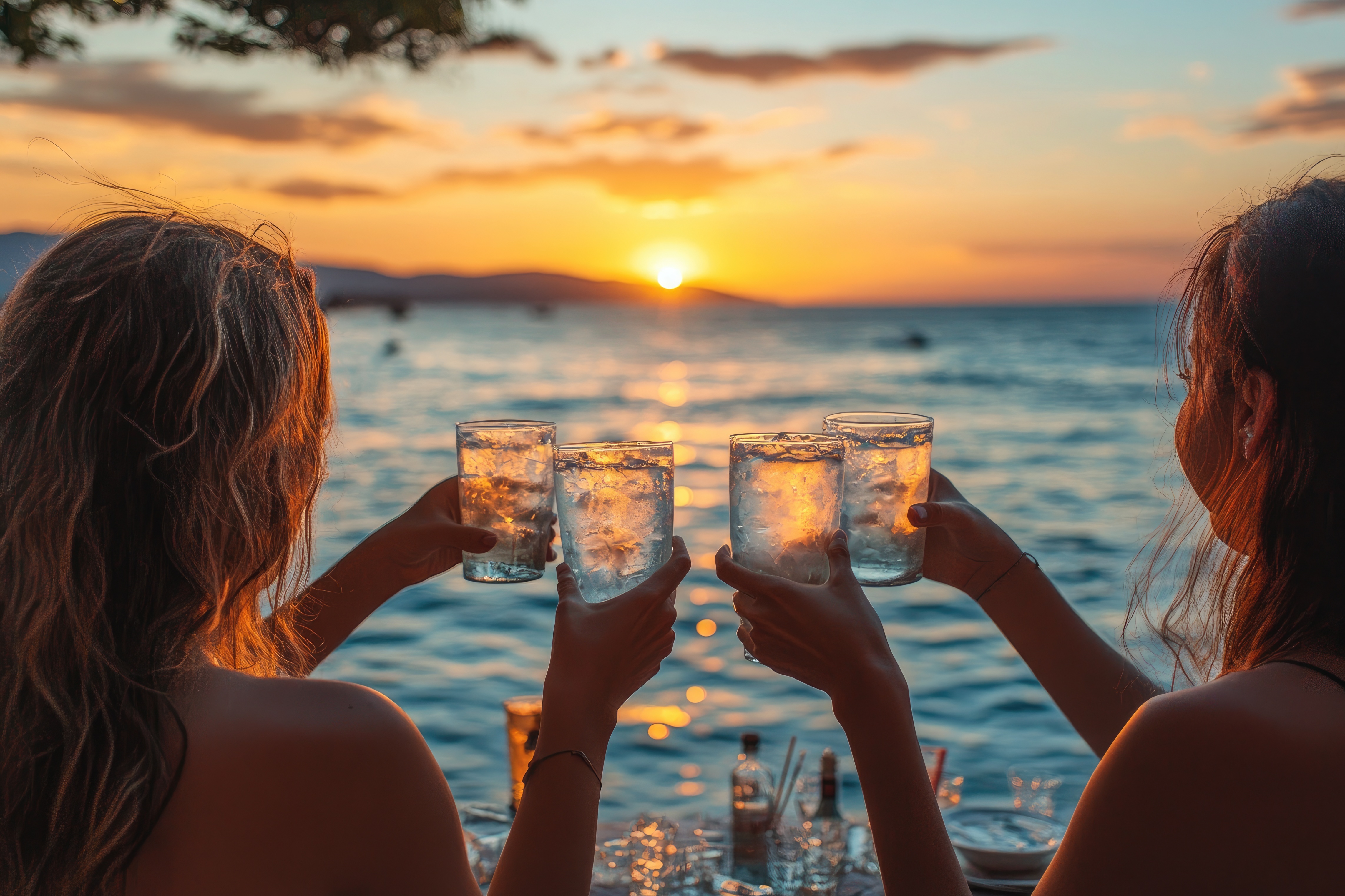 Friends cheers with drinks at sunset