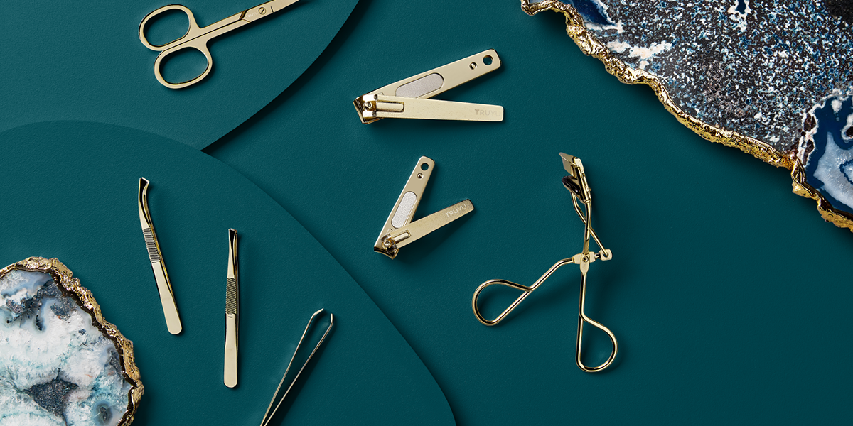 TRUYU gold cosmetic tools laid out on a navy background with gemstones in the background