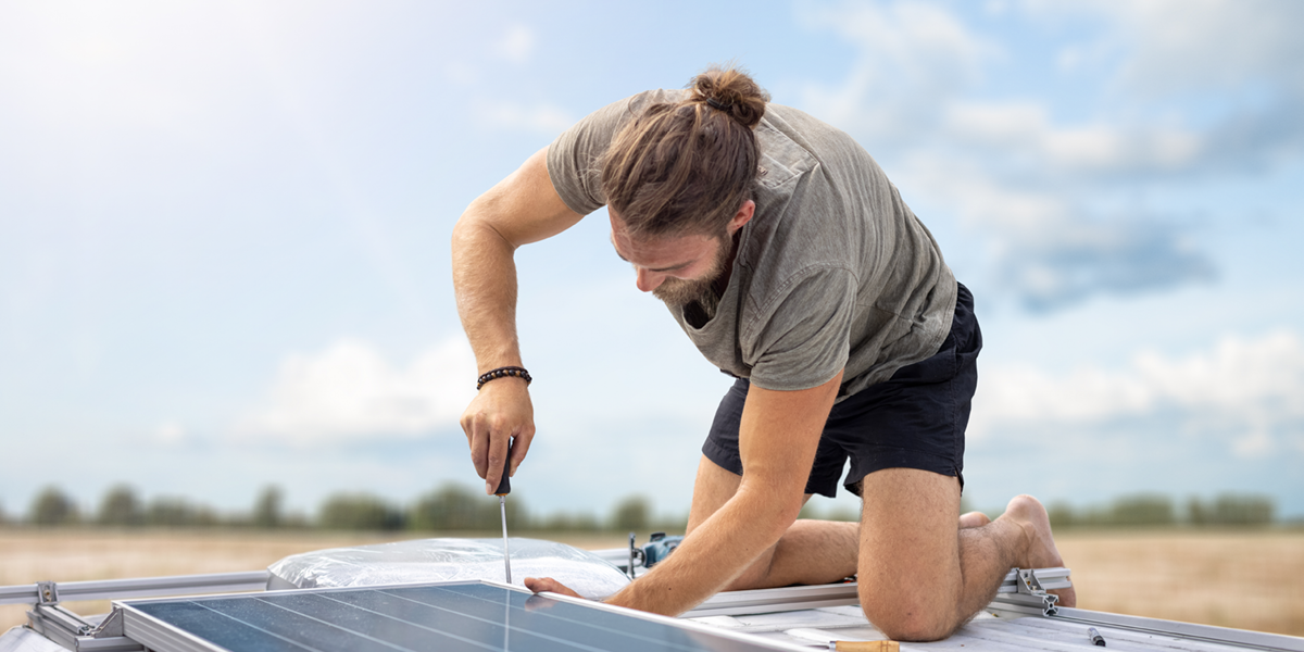 Person building solar panel on caravan