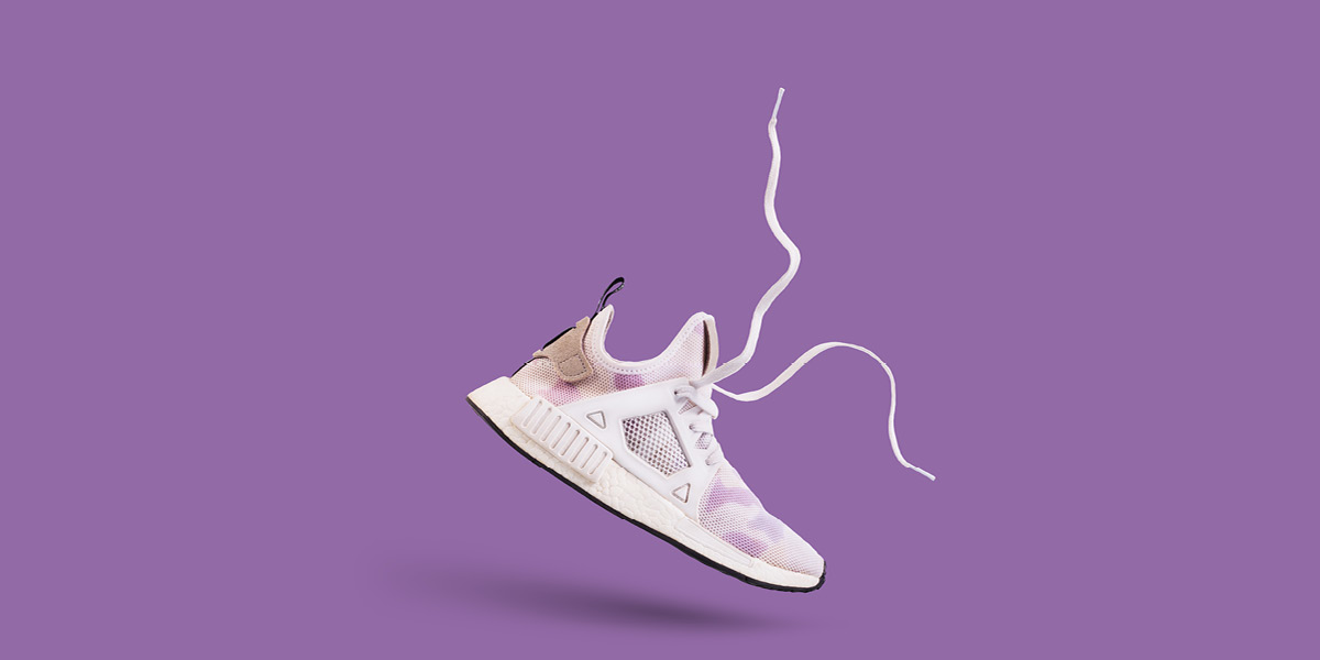 Trainer floating in mid air against a purple background