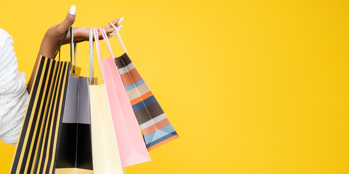 Woman holding shopping bags on yellow surface