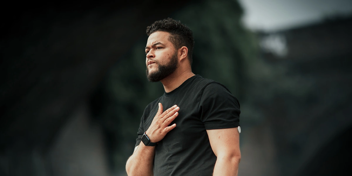 Man standing with arm to chest looking into the distance