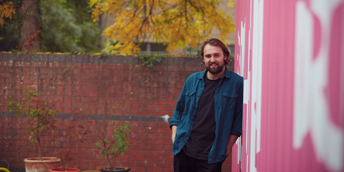 Man standing against pink storage container