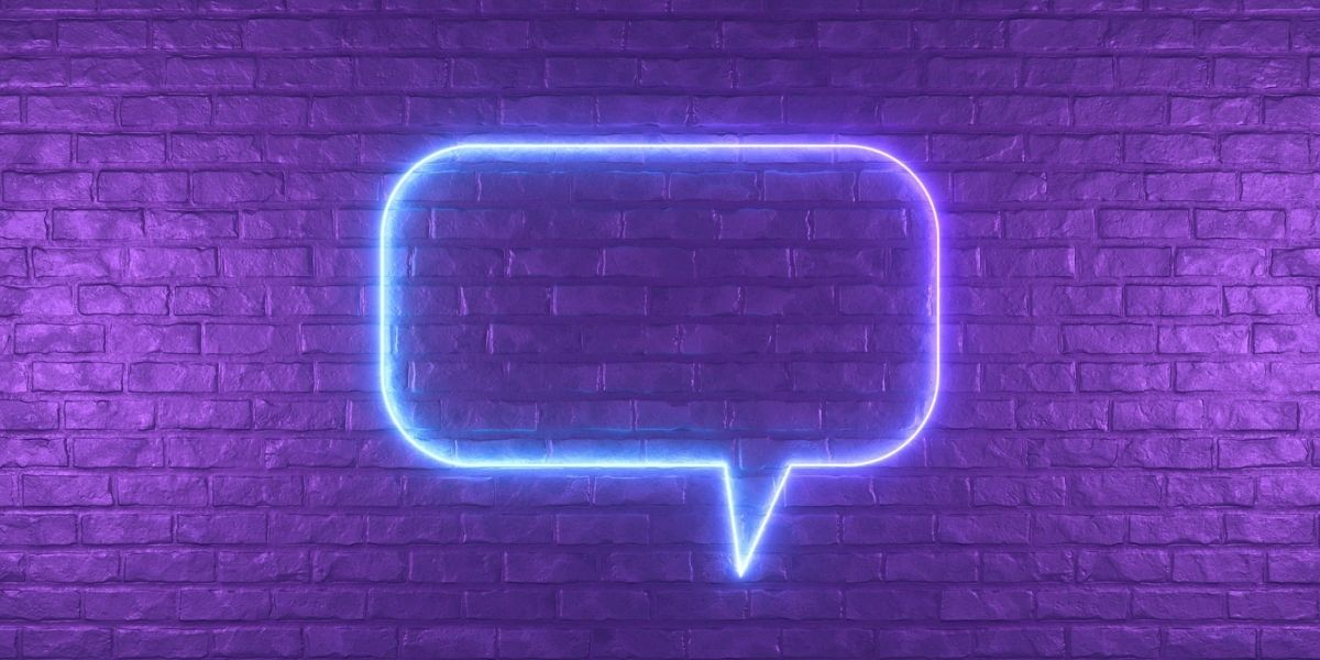 Neon blue comment symbol on purple brick wall