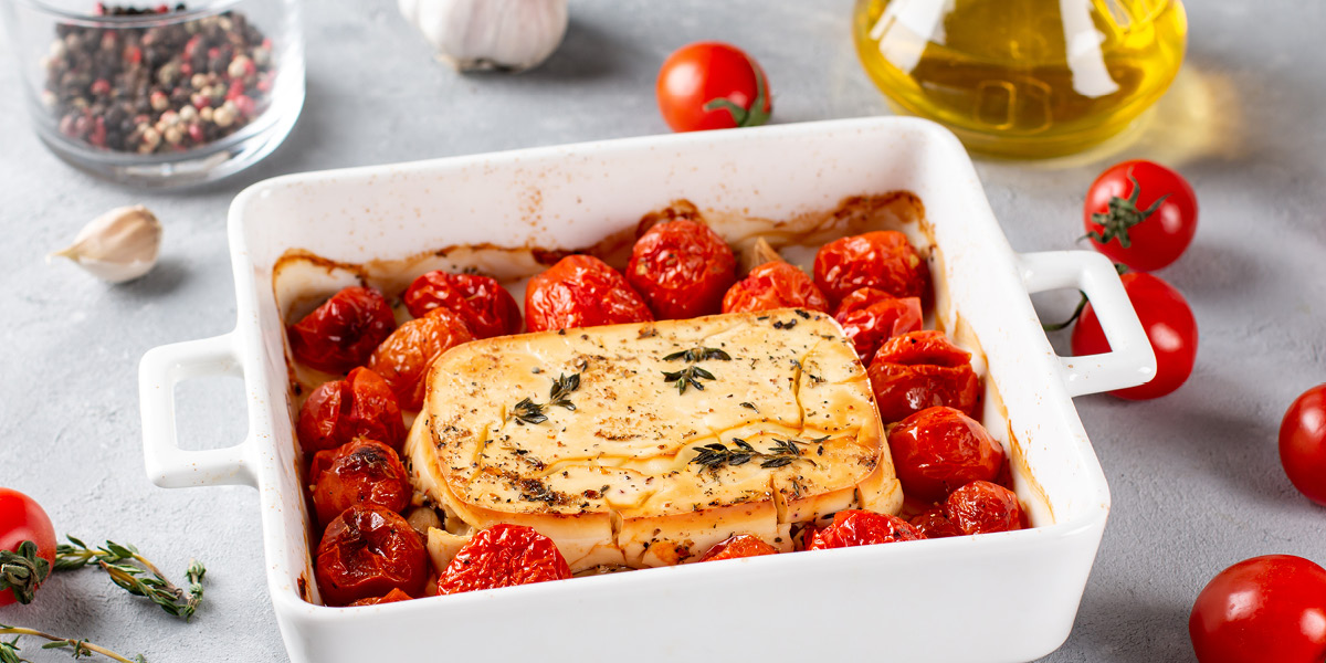 White casserole dish with cherry tomatoes, cheese and olive oil cooked