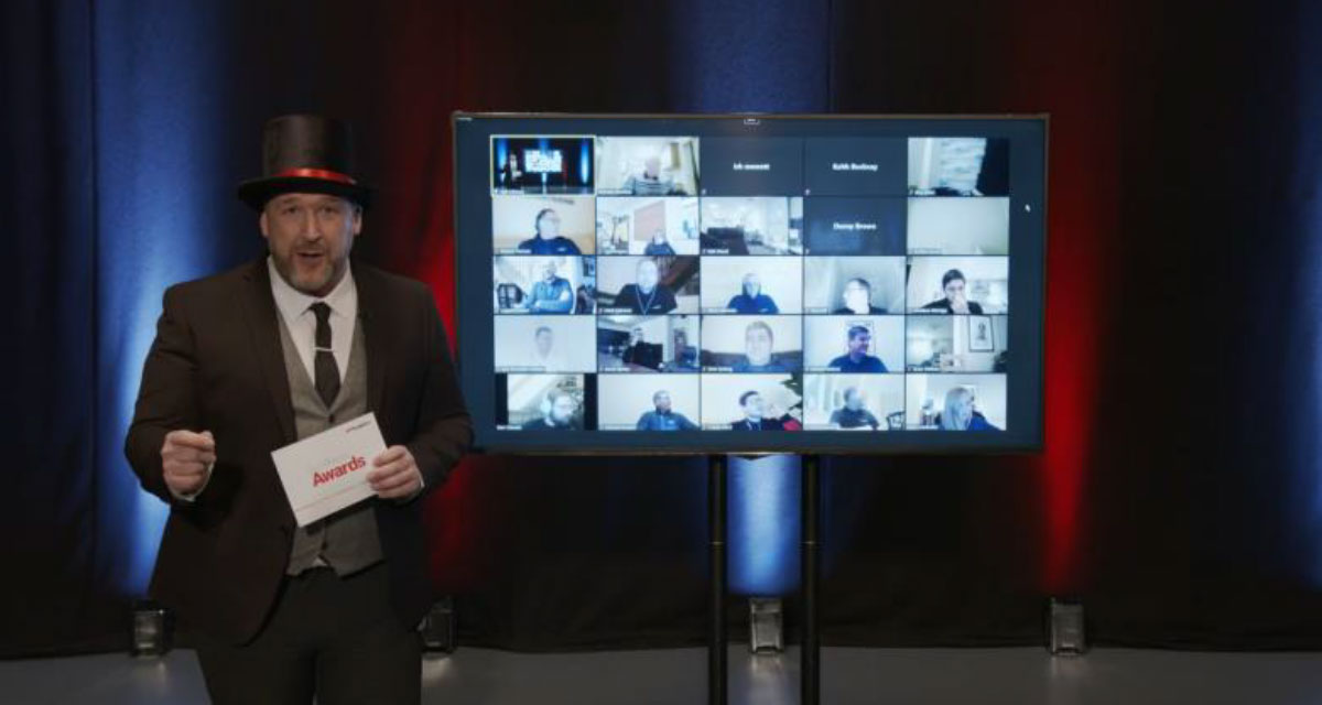 Person wearing a top hat standing next to a TV screen presenting to the camera