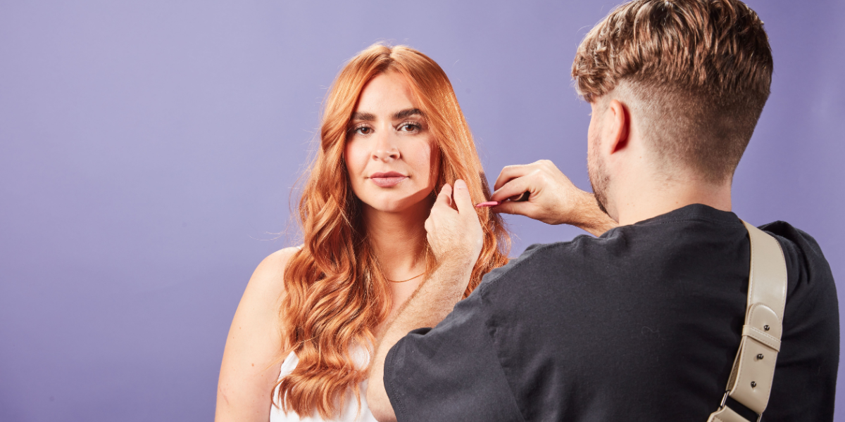 A man styling a young woman's hair ready for a photoshoot