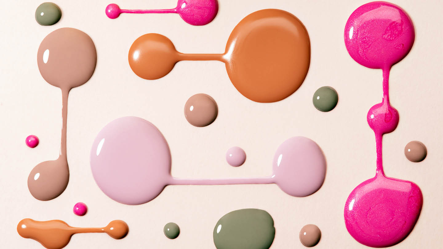 Blobs of makeup products in pink, green, brown and orange arranged on a cream background