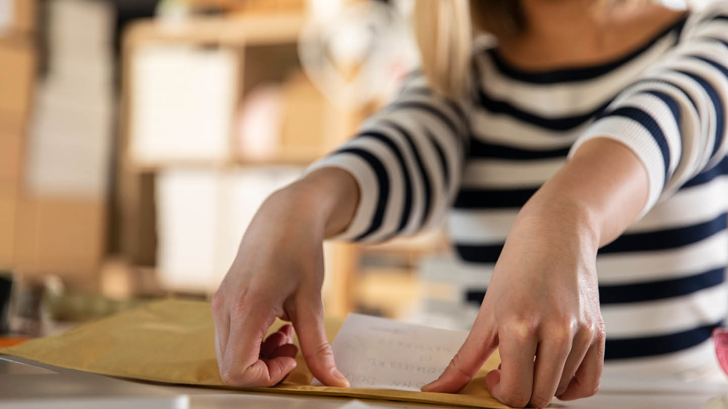 Person in a striped top putting label on a cardboard box