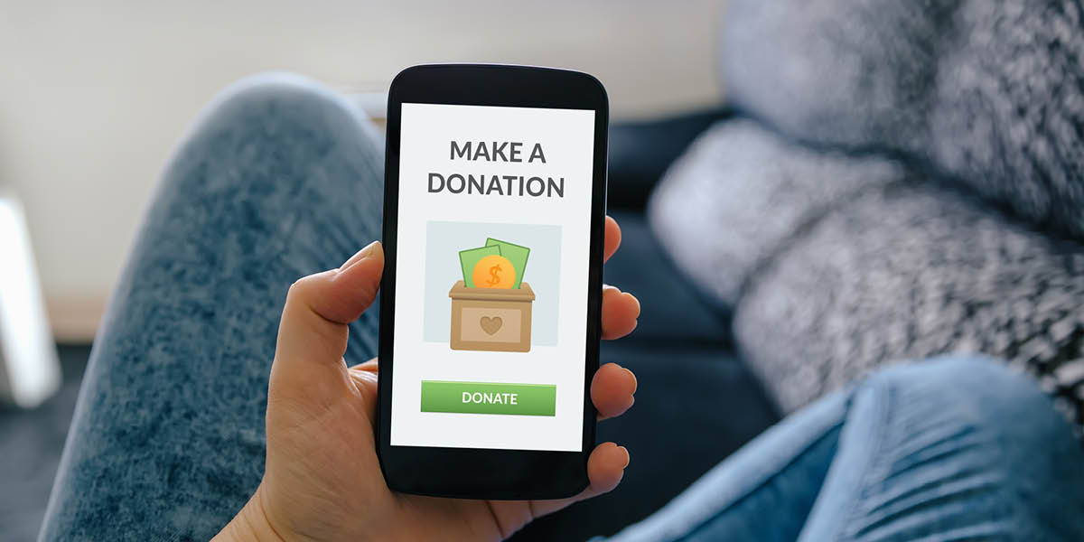 Person sitting on a sofa making a donation on a mobile